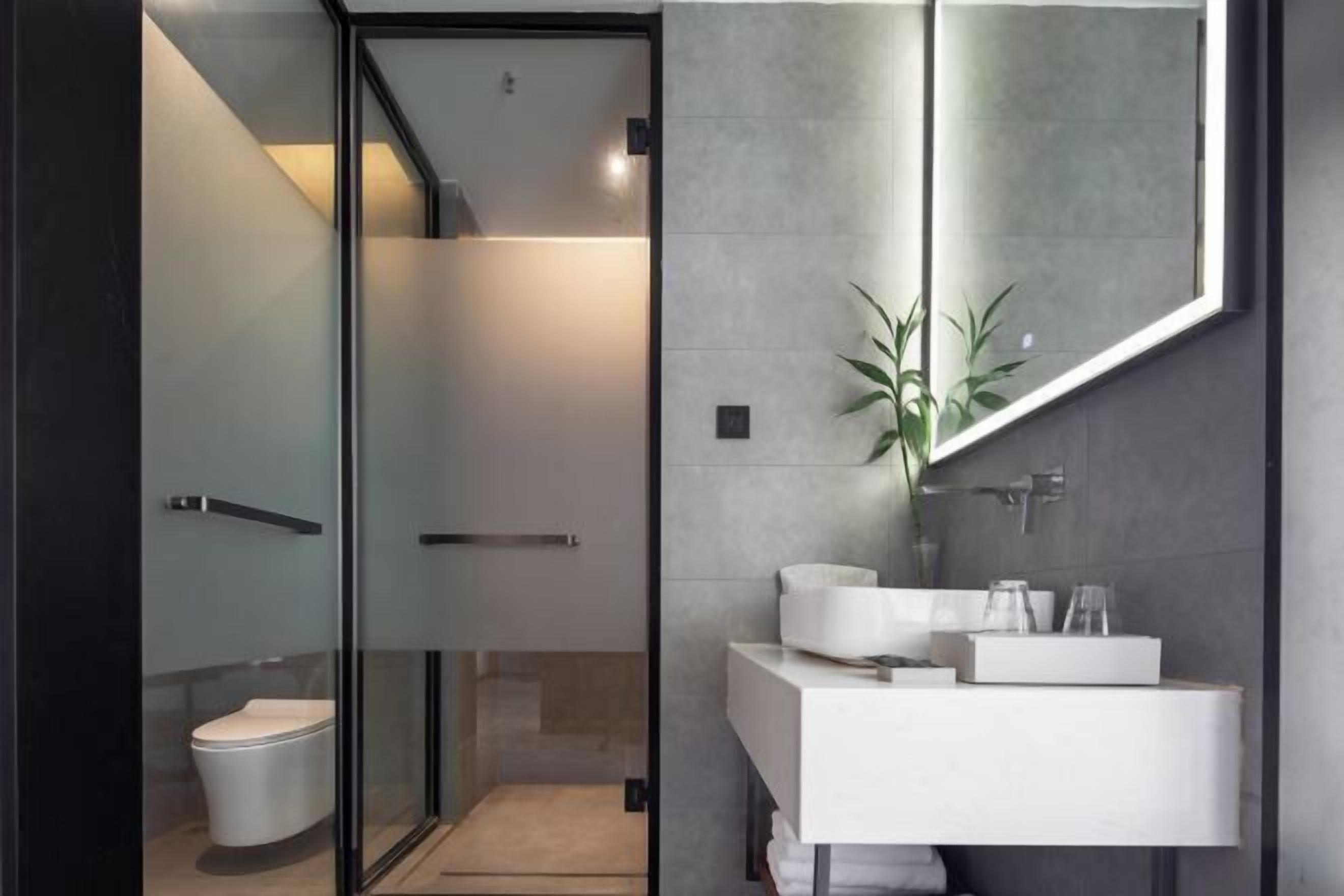 A modern bathroom with a glass shower enclosure, a white sink, and a large mirror.