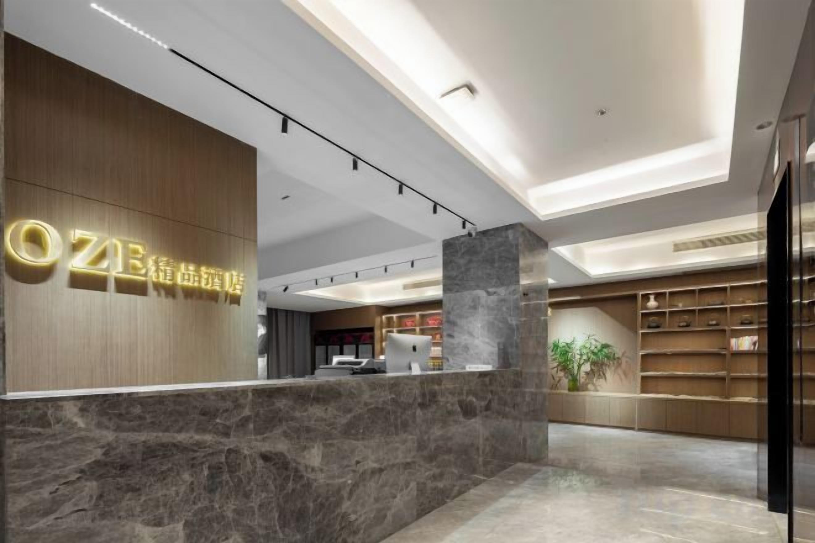 A hotel reception area with a marble counter, wooden paneling, and a modern ceiling design.