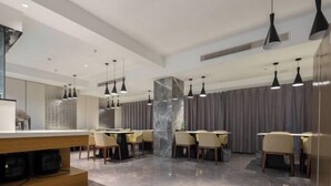 Un comedor moderno con varias mesas y sillas, iluminación colgante y una pared decorativa de mármol.