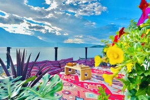 A balcony with a patterned rug, a small wooden table, and a view of the sea. - ayan house (Dali City)