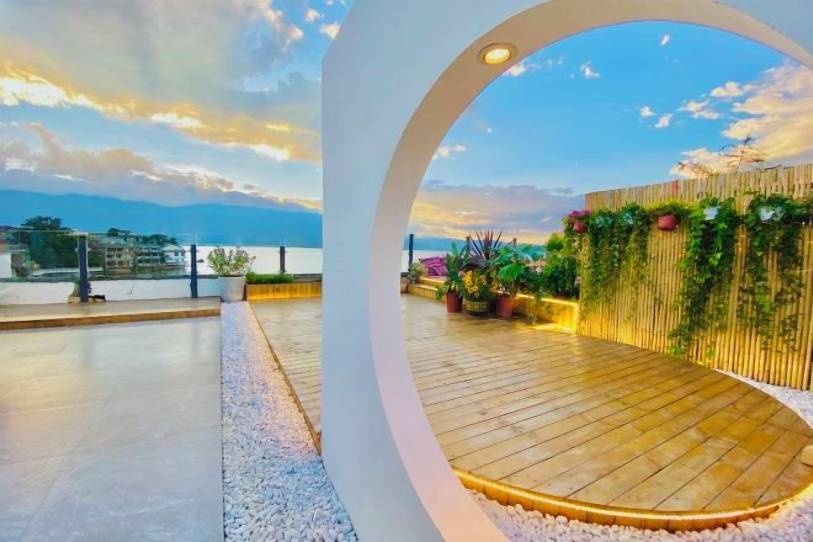 Una terraza en la azotea con piso de madera, barandas blancas y vista al mar.
