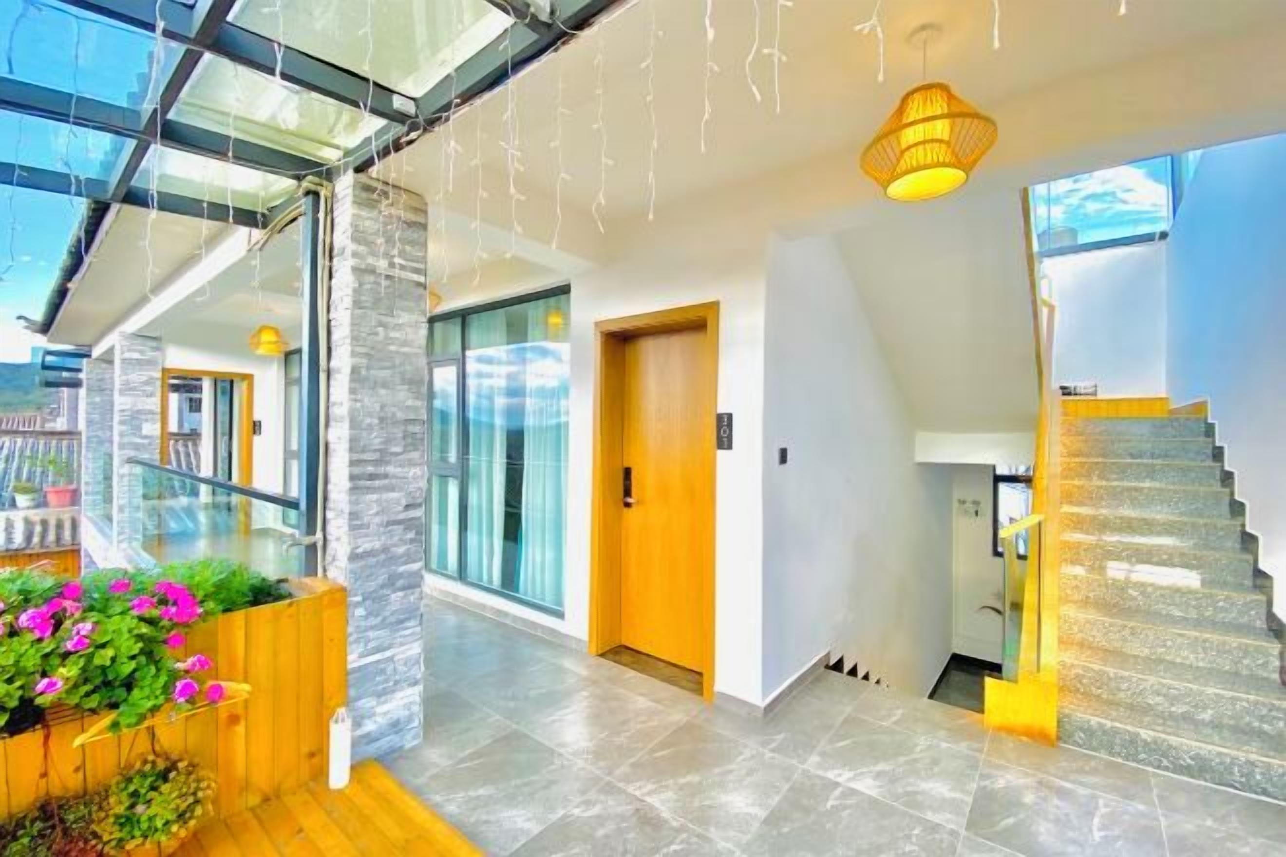 Un interior moderno con una escalera, un banco de madera con flores y una pared de vidrio.
