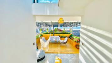 Un interior moderno con suelo de madera, paredes blancas y una zona de estar con mesa y sillas.