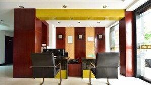 A reception area with a desk, two chairs, and a wall with framed certificates. - XINYUN BUSINESS HOTEL (Zhoushan)