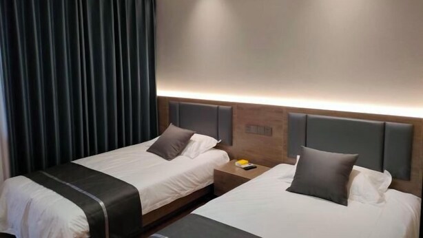 A hotel room with two beds, a nightstand, and a large window with curtains. - XINYUN BUSINESS HOTEL (Zhoushan)