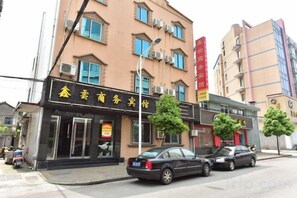 Un bâtiment dont la façade présente des caractères chinois, avec deux voitures garées devant et un lampadaire.
