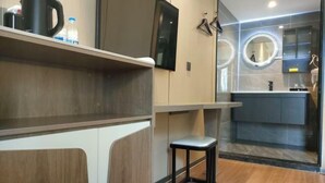 A modern bathroom with a vanity, a stool, and a mirror with a circular frame. - XINYUN BUSINESS HOTEL (Zhoushan)
