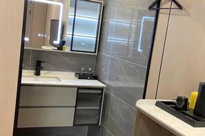 A modern bathroom with a large mirror, a sink, and a toilet.