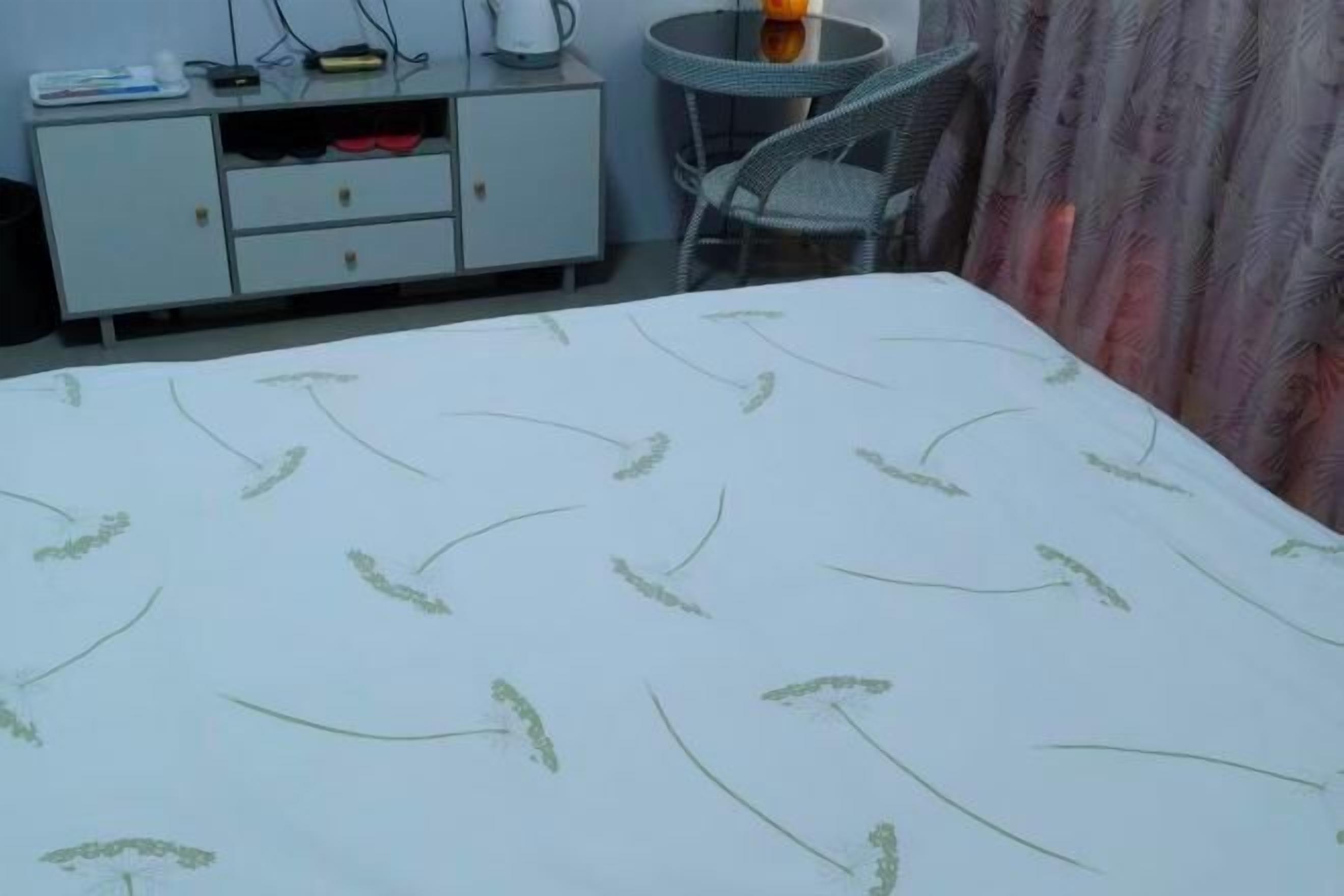 Ein Hotelzimmer mit Bett, kleinem Tisch mit Stuhl, Minibar und Vorhang.