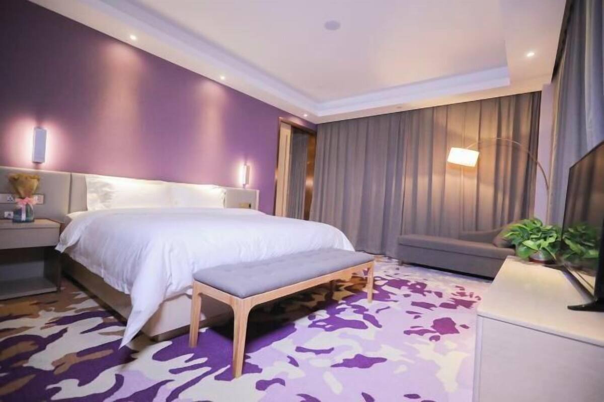 Una habitació d'hotel moderna amb un llit gran, una banca, un escriptori i un sofà.