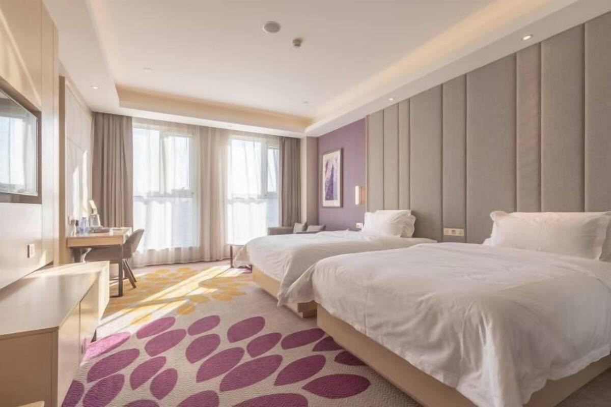 Habitació d'hotel amb dos llits, un escriptori i una finestra gran.