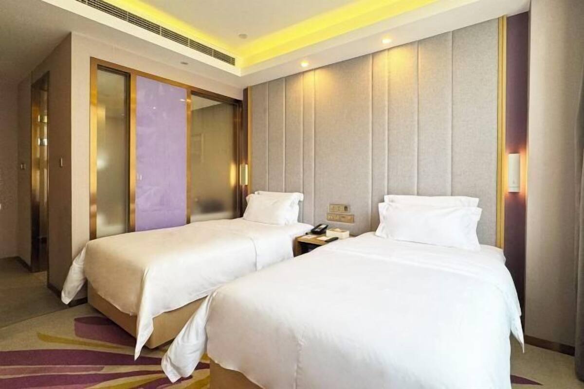 Habitació d'hotel amb dos llits, un mirall gran i un disseny modern.