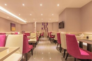 A restaurant with booths and tables, a flat-screen TV mounted on the wall, and a patterned wall decoration.