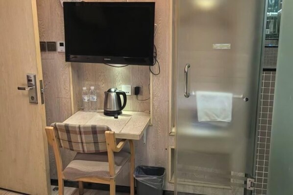 A small kitchenette with a table, chair, TV, kettle, and trash bin. - Super 8 Hotel (Beijing Huayuanqiao Subway Station Capital Normal University) (Beijing)
