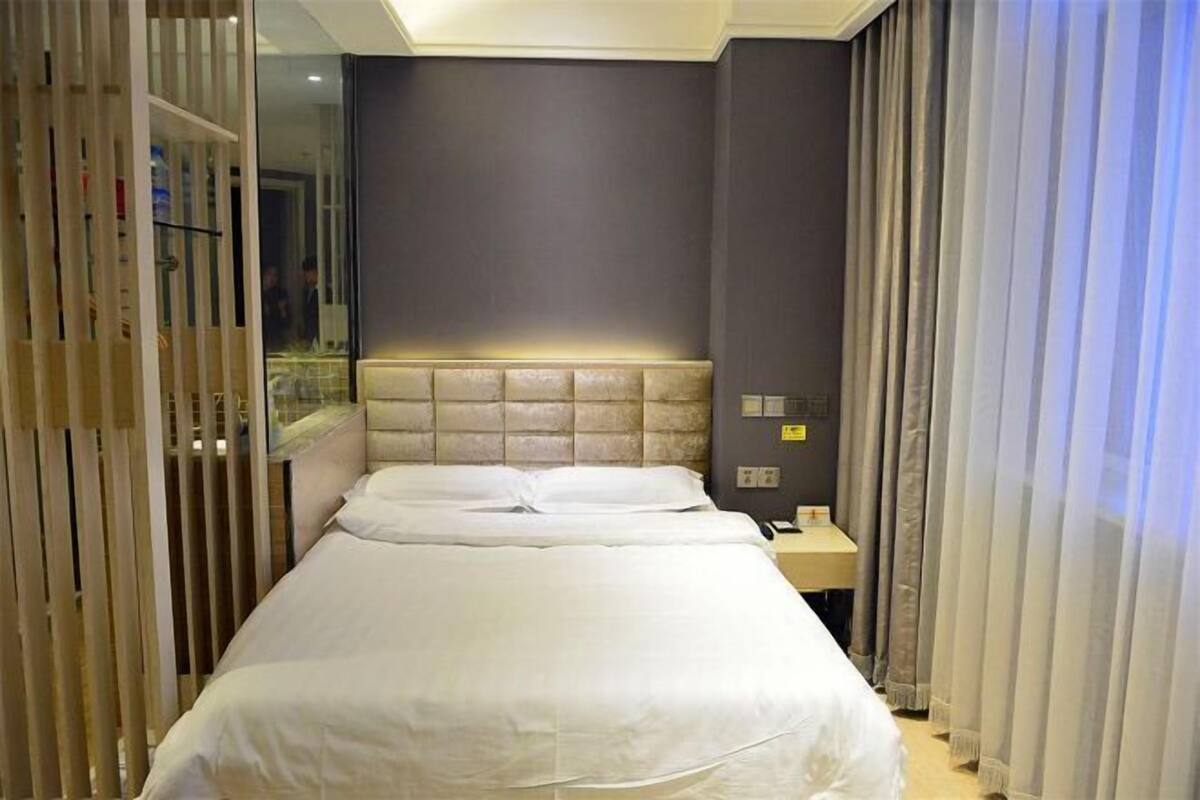 A hotel room with a large bed, a bedside table, and a mirror.