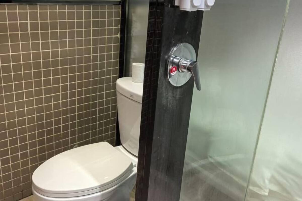 A bathroom with a toilet, a shower enclosure, and a tiled wall.
