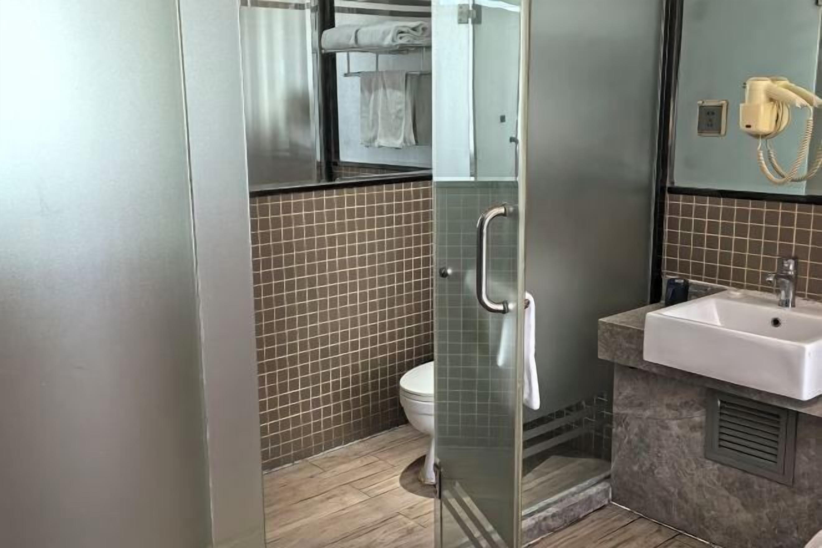 A modern bathroom with a glass shower enclosure, a white toilet, and a sink with a telephone.