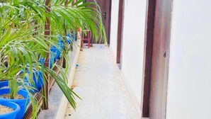 A corridor with a tiled floor, potted plants, and doors leading to rooms. - Hotel ornate  (Chandauli)