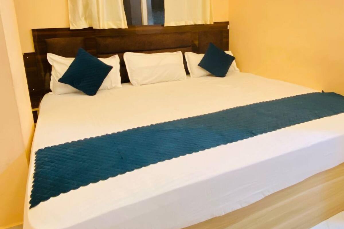 Un dormitorio con cama, ventilador de techo, ventana con cortinas y cabecero de madera.