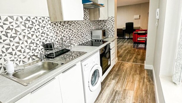 Een kleine keuken met een wasmachine, een magnetron en een spoelbak.