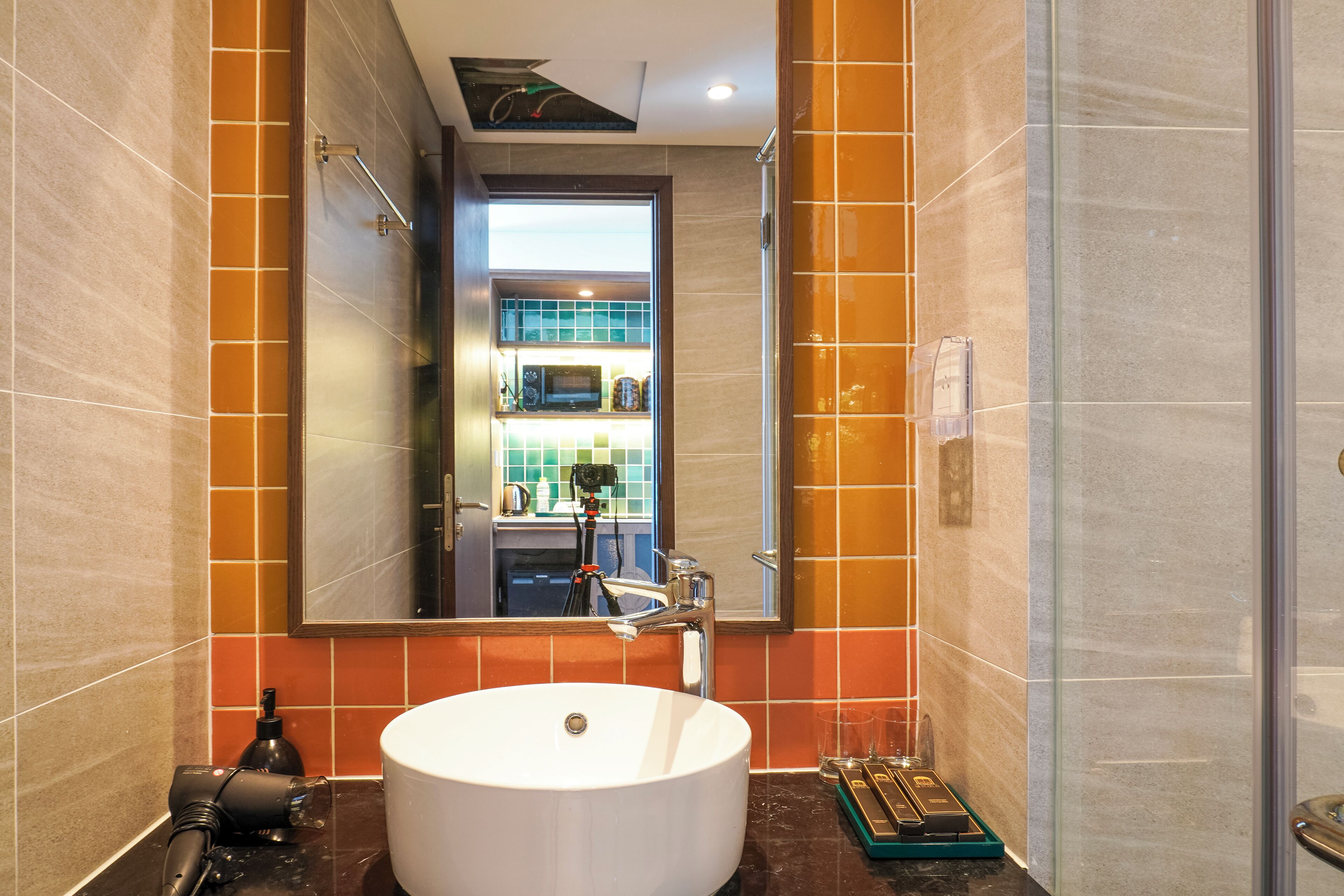 A modern bathroom with a large white sink, a mirror, and a shower area.
