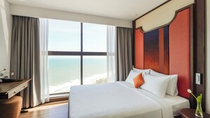 A hotel room with a large bed, a desk, and a view of the ocean. - Sea Senses HomeStay (Mui Ne)