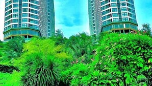 Two tall, modern buildings with a curved design, surrounded by lush green vegetation. - Sea Senses HomeStay (Mui Ne)