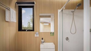 A compact bathroom with a window, a sink, a mirror, and a shower. - The Mini Chalet by Tiny Away (Mundoolun)