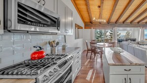 Una cocina moderna con electrodomésticos de acero inoxidable, vigas de techo de madera y vistas al exterior.