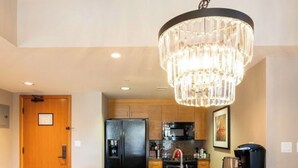 Una cocina moderna con encimeras de granito, un refrigerador de acero inoxidable y una cafetera negra.