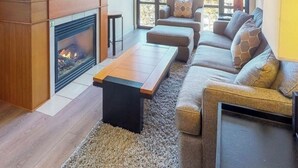 Una sala de estar moderna con chimenea, televisor grande montado en la pared y un juego de sofás.