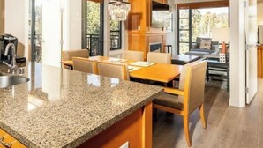 Una cocina moderna con encimeras de granito, gabinetes de madera y un comedor con candelabro.