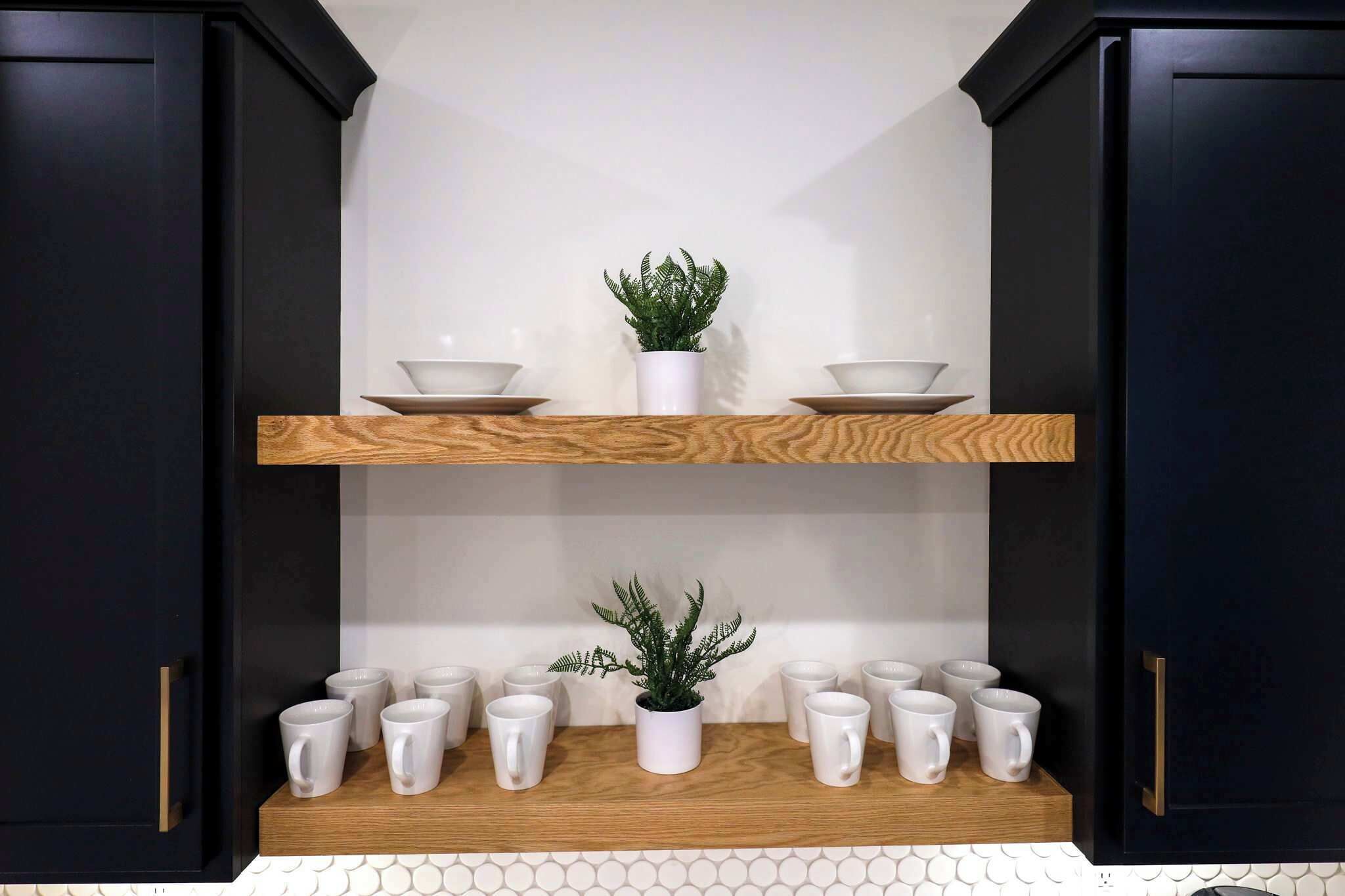 Een keuken met donkere kastjes, een wit aanrecht en een potplant op de plank.