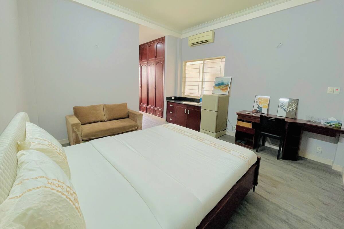 A bedroom with a bed, a sofa, a desk, and a wardrobe.