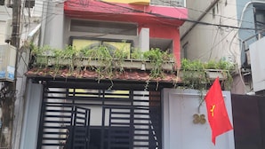 Un edificio con techo rojo, pared amarilla y portón negro. Una bandera ondea en el lado derecho del portón.