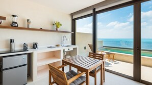 Una cocina moderna con vistas al océano, un comedor con mobiliario de madera y un pequeño balcón con vistas.