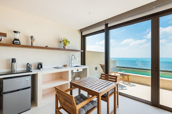 Une cuisine moderne avec vue sur l’océan, un coin repas avec des meubles en bois et un petit balcon offrant également une vue.