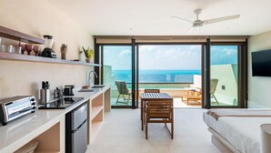 Una cocina moderna con vista al océano, un comedor con mesa y sillas, y un dormitorio con cama.