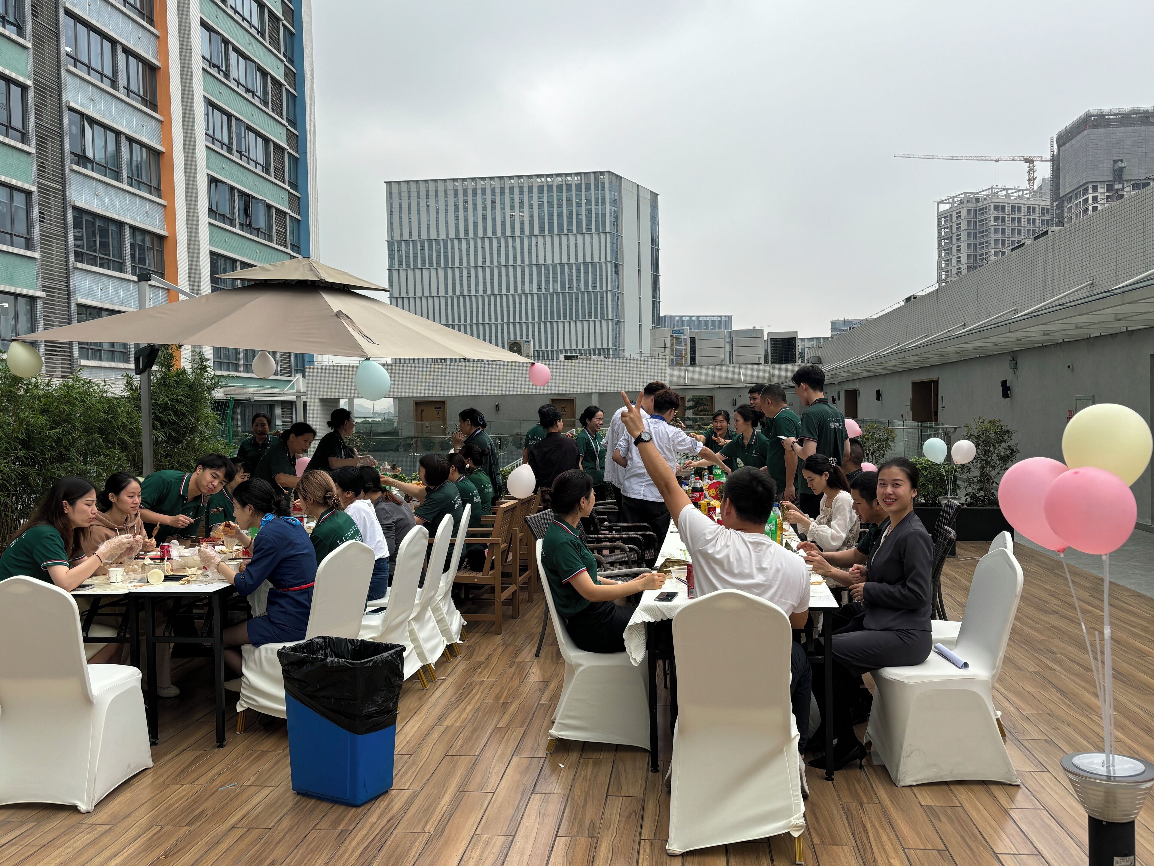 A rooftop dining area with tables and chairs, surrounded by buildings.