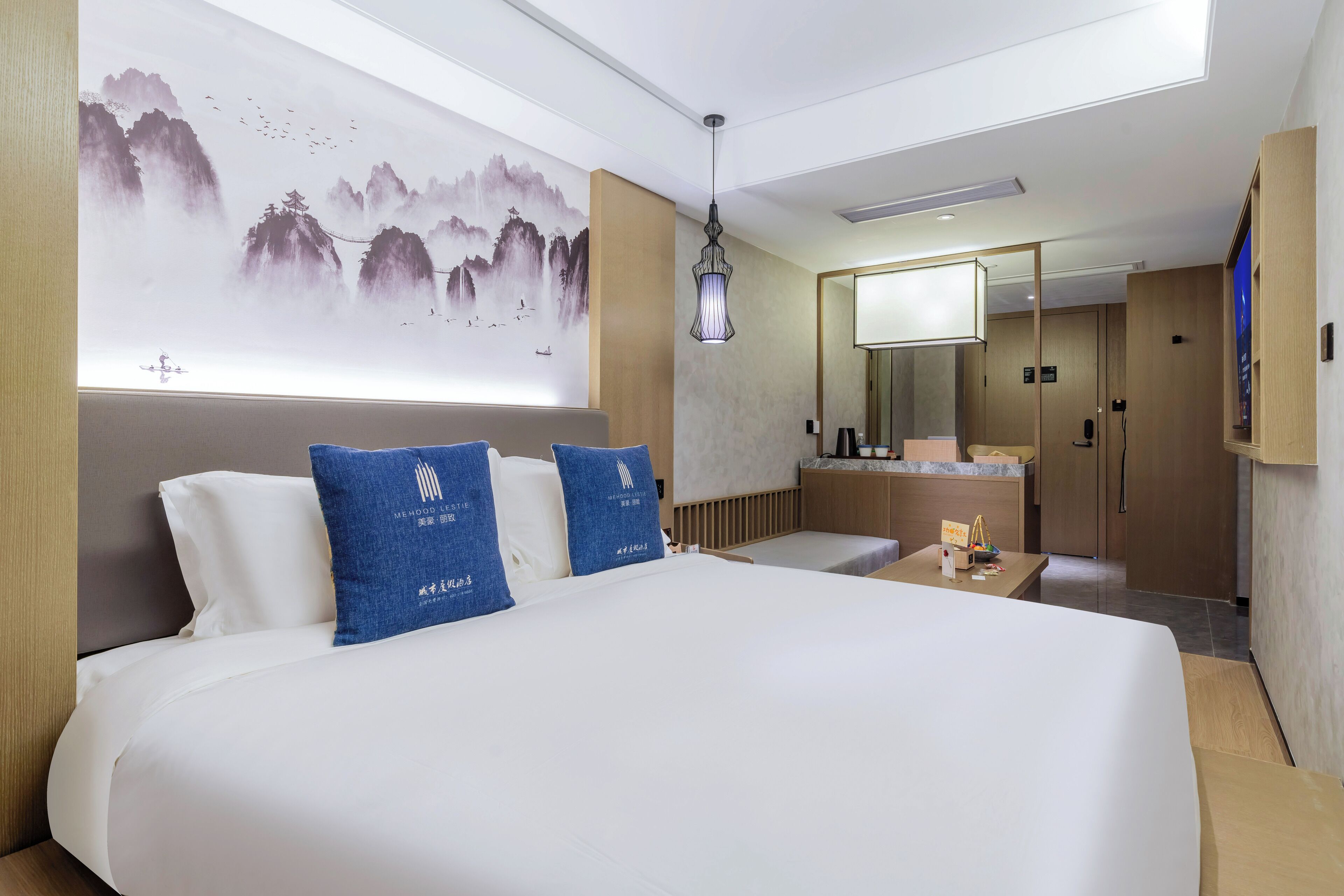 A hotel room with a large bed, a desk, a mirror, and a wall with a painting.
