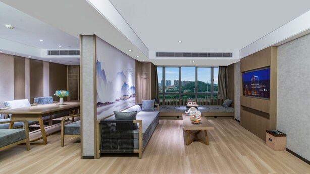 A modern living room with a wooden floor, a sofa, a dining table, and a large window offering a city view. - LIZ International Hotel Guangzhou Olympic Sports Center International Financial City Branch - Free Shuttle Bus to Canton Fair Complex During Canton Fair Period (Guangzhou)