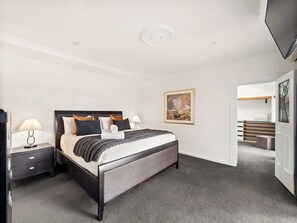 A modern bedroom with a bed, nightstands, and a painting on the wall.