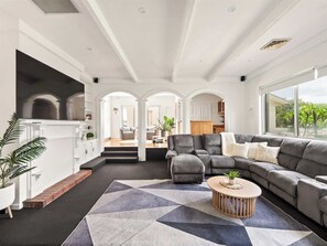 A spacious living area with a sectional sofa, a coffee table, and a view of the kitchen.