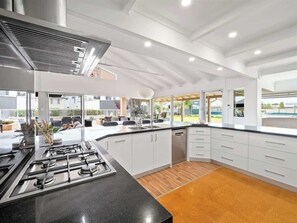 A modern kitchen with a gas stove, white cabinets, and a view of the outdoors.