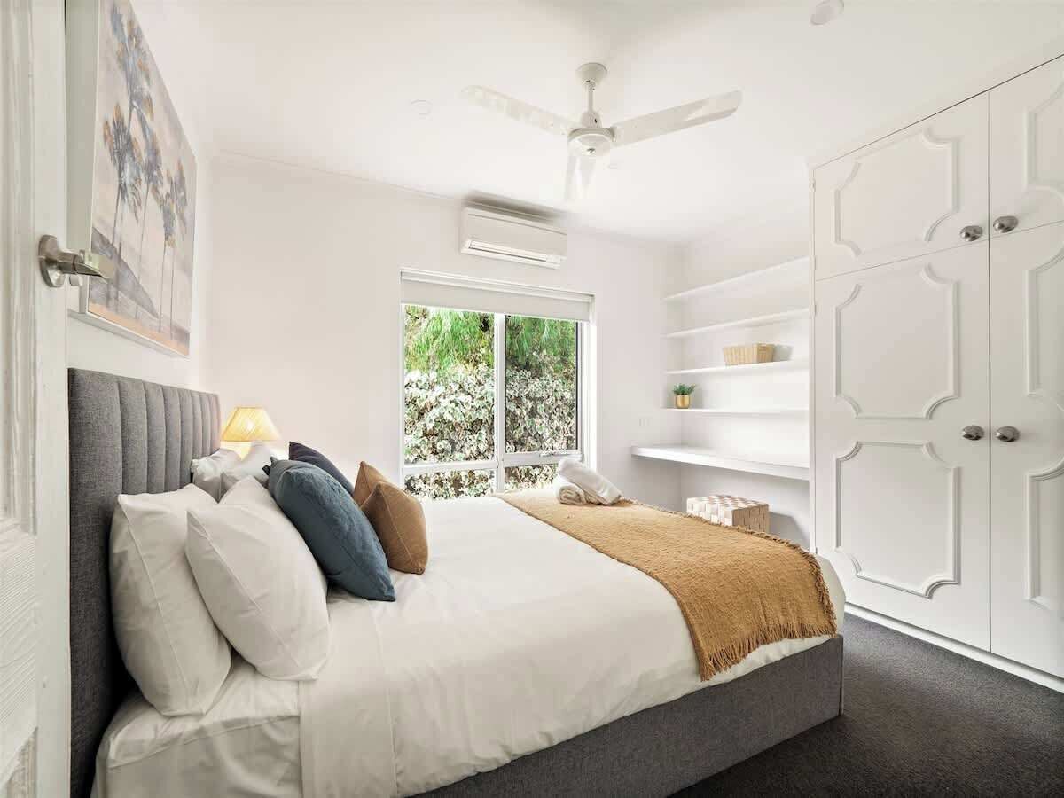 Ein Schlafzimmer mit Bett, Deckenventilator, Fenster und Kleiderschrank.