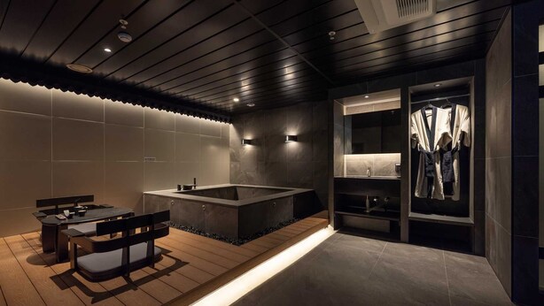 Ein modernes Badezimmer mit Badewanne, Waschtisch mit Spiegel und einer Sitzecke mit Tisch und Stühlen.