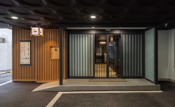 Fachada moderna de edificio con madera y puerta de cristal que da acceso al interior.