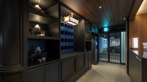 Ein stilvoller Lounge-Bereich mit modernem Design, der dunkle Holzvertäfelung, eingelassene Beleuchtung und einen Glastür-Eingang aufweist.