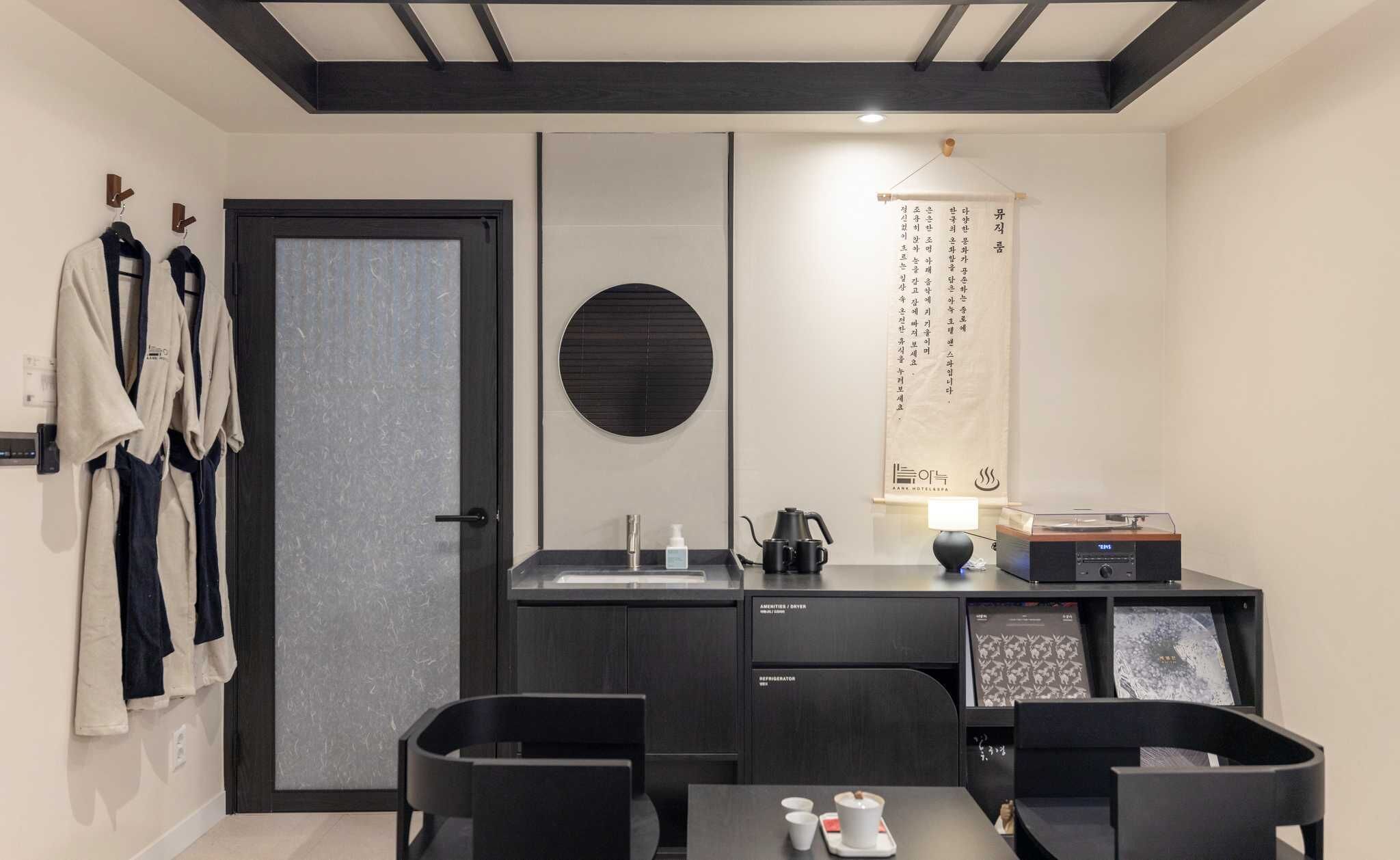 Una habitación de hotel moderna con kitchenette, zona de comedor y armario con batas.