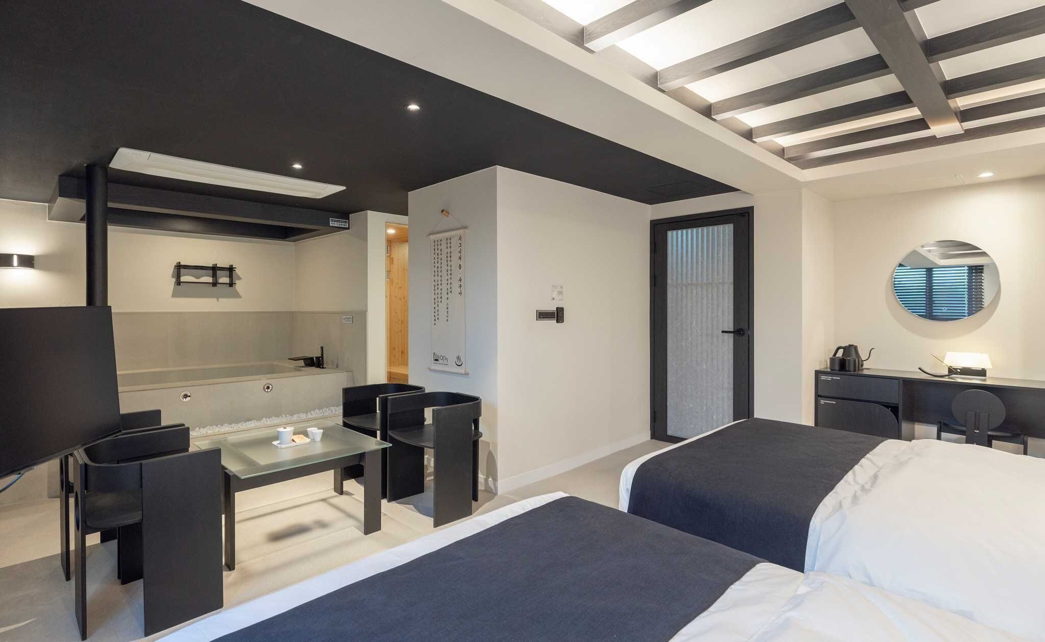 Ein modernes Hotelzimmer mit Bett, Schreibtisch, Stuhl, kleinem Tisch und Badezimmer.